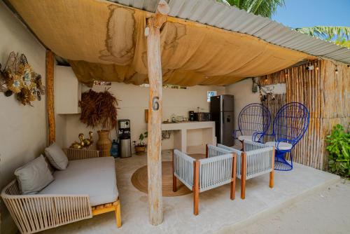 a patio with a couch and chairs under an umbrella at Arena y Mar Seaside Glamping - Adults Only by The Spot Rentals in El Cuyo