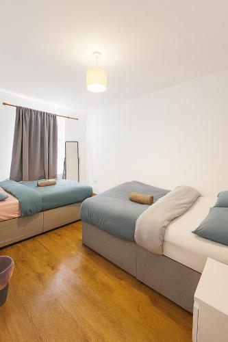 two beds in a room with white walls and wood floors at Beautiful 4 bedrooms house, 7 walk to train station in Plumstead