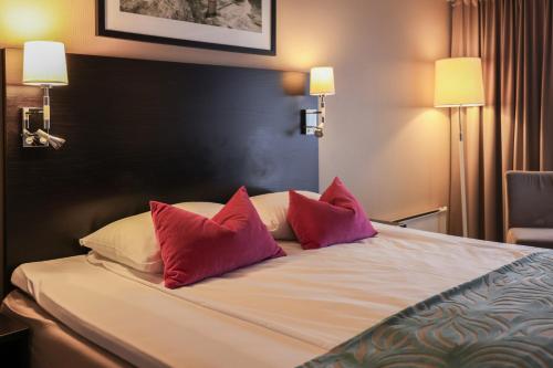 a bed with three red pillows on top of it at Quality Hotel Florø in Florø