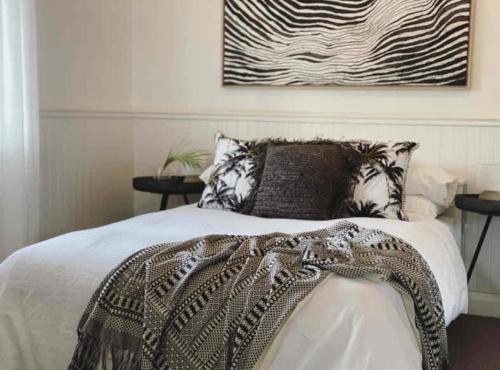 a bedroom with a bed with a blanket and two tables at Tosca Elegant Merewether Beach House with Pool in Merewether