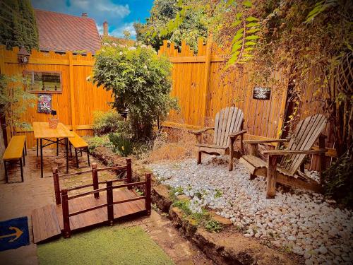 a garden with benches and a table and a fence at Logement insolite La cachette des Pirates, Jacuzzi, ciné et pop corn in Montreuil-sur-Thérain
