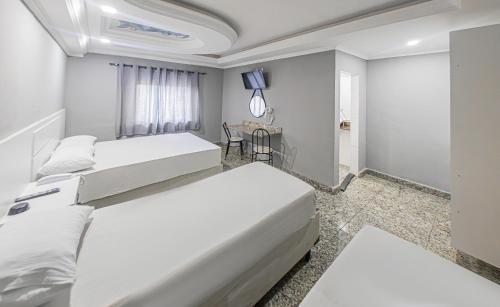 a bedroom with two beds and a table at Hotel Monte Palma - São Paulo Próximo a Arena Neo Química in Sao Paulo