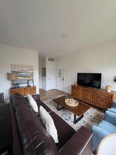 a living room with a brown leather couch and a tv at Downtown Traverse City Capri Condo 316 in Traverse City