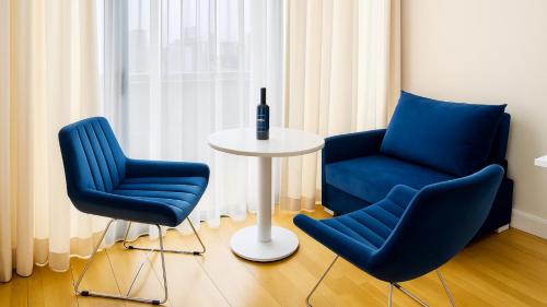 two blue chairs and a table with a bottle of wine at Orbi City - Sea View Aparthotel in Batumi in Batumi