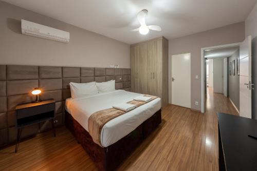 een slaapkamer met een groot bed, een tafel en een lamp bij B Homy Alegre in Sao Paulo