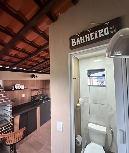 a bathroom with a toilet and a sign on the wall at Acesso à Praia Ar Condicionado Conforto Garantido! in Saquarema