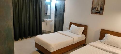a small bedroom with two beds and a sink at ZAHIR RESIDENCY calicut in Kozhikode