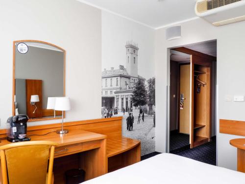 a bedroom with a mirror and a desk with a bed at Mercure Czestochowa Centrum in Częstochowa