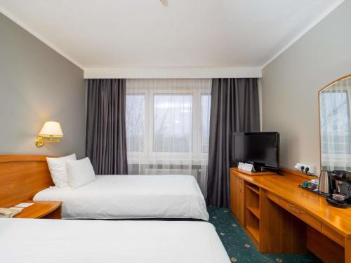 a hotel room with two beds and a television at Mercure Czestochowa Centrum in Częstochowa