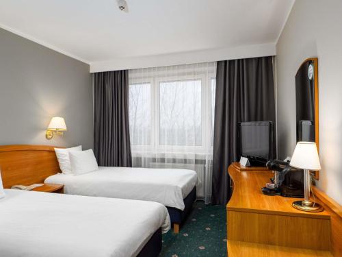 a hotel room with two beds and a television at Mercure Czestochowa Centrum in Częstochowa