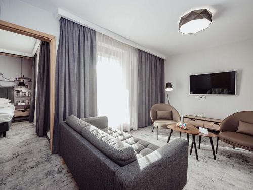 a living room with a couch and a tv at Mercure Jelenia Góra in Jelenia Góra