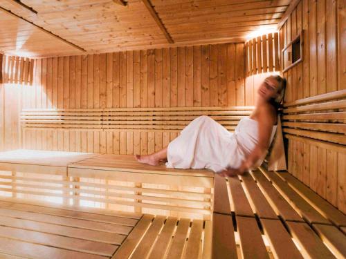 a woman is sitting in a sauna at Mercure Gdynia Centrum in Gdynia