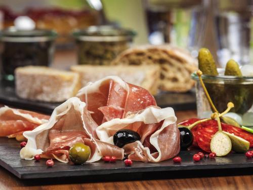 a cutting board with meat and fruits and vegetables at Mercure Gdynia Centrum in Gdynia