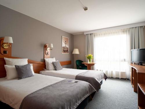 a hotel room with two beds and a television at Mercure Cieszyn in Cieszyn