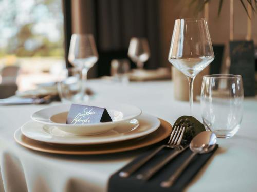 a table with plates and forks and a wine glass at Mercure Cieszyn in Cieszyn