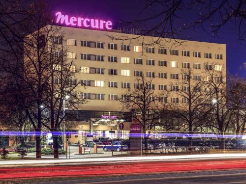 a large building with a purple sign on it at Hotel Mercure Toruń Centrum in Toruń
