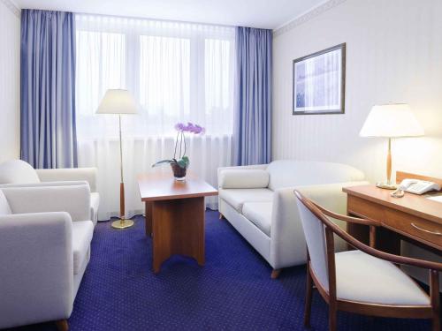 a living room with a couch and a table with a desk at Hotel Mercure Toruń Centrum in Toruń