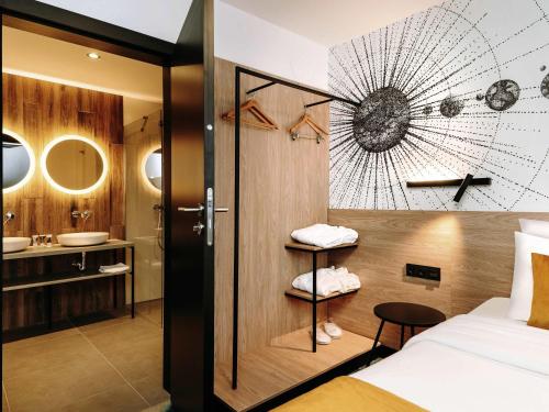 a bedroom with a bed and a bathroom with a sink at Hotel Mercure Toruń Centrum in Toruń