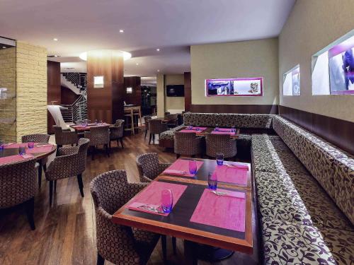 a restaurant with tables and chairs with pink napkins at Hotel Mercure Toruń Centrum in Toruń