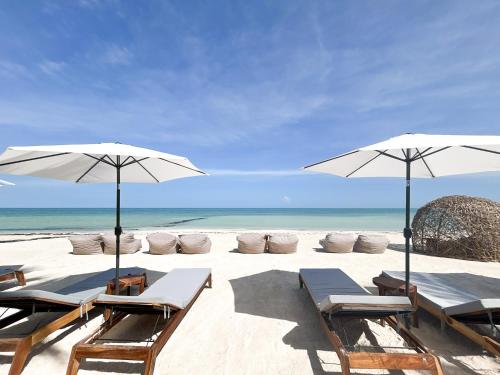 a beach with chairs and umbrellas and the ocean at Ana y Jose Hotel & Beach Club Holbox in Holbox Island