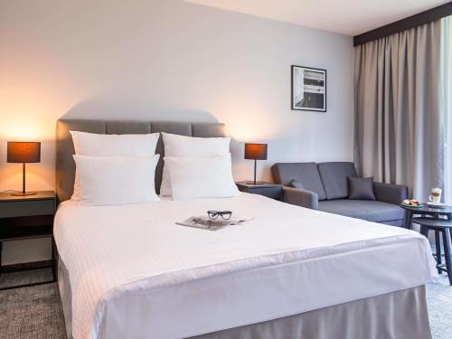 a hotel room with a large white bed and a chair at Mercure Karpacz Skalny in Karpacz