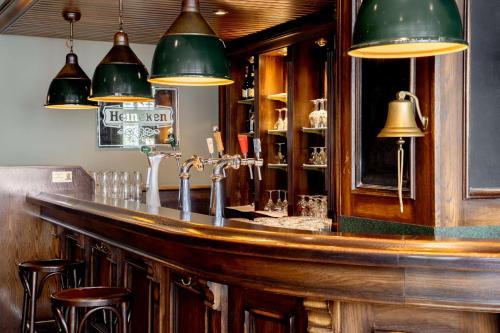 a bar in a restaurant with green lamps and stools at NH Amsterdam Noord in Amsterdam