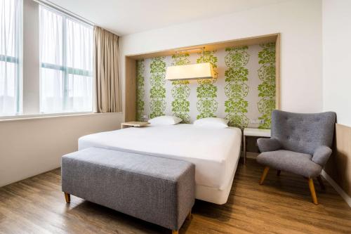 a hotel room with a bed and a chair at NH Amsterdam Noord in Amsterdam