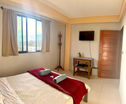 a bedroom with a bed and a window and a television at Alojamiento Bilbao in Quillacollo