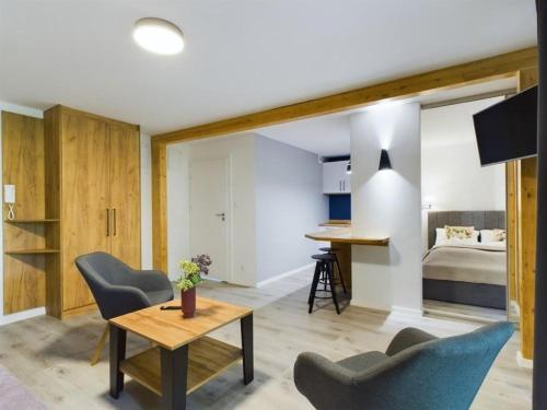 un soggiorno con tavolo, sedie e un letto di Apartamenty Dabrowka Plus - w lesie, prywatny parking, sauna, park a Jelenia Góra