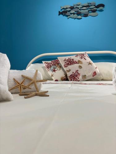 a white bed with pillows and a starfish on it at STELLA MARINA Apartment in Mascali