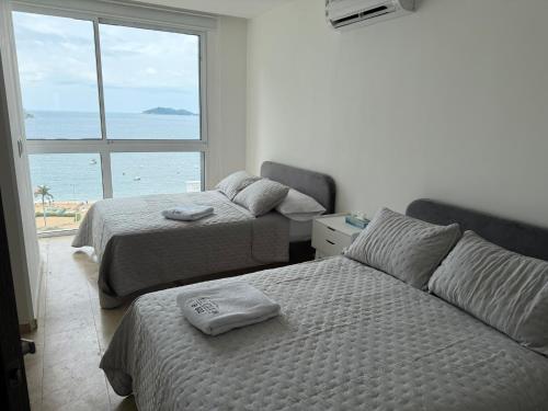 two beds in a bedroom with a view of the ocean at Departamento de 4 recámaras con vista al mar in Acapulco