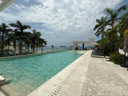 une piscine avec des palmiers et l'océan dans l'établissement Departamento para 12 personas con vista al mar, à Acapulco