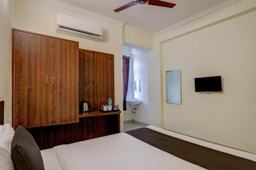 a bedroom with a bed and a tv on the wall at Hotel O Shiridi Residency in Vidya Nagar