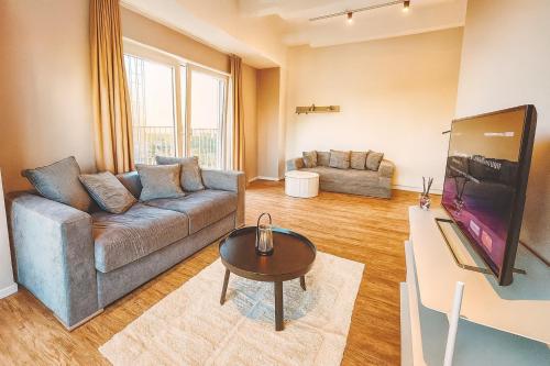 a living room with a couch and a table at Homely! Skyview 2-Room Apartment, Airport, Fair, Rooftop, Gym! in Frankfurt/Main