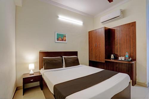 a bedroom with a bed and a wooden cabinet at Hotel O Shiridi Residency in Vidya Nagar