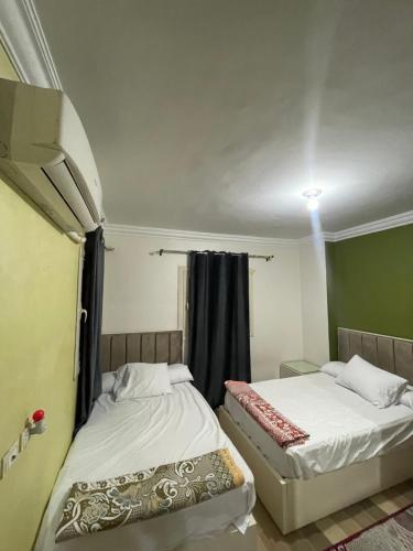 two beds in a small room with a window at كورنيش نيل in Jazīrat al Badrashayn