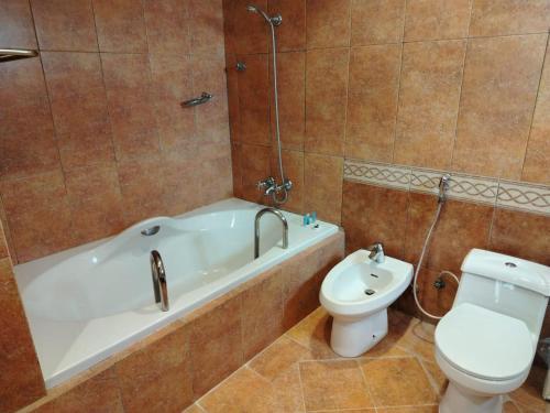 a bathroom with a tub and a toilet and a sink at Al-Borg Al-Watheer Serviced apartments in Jazan