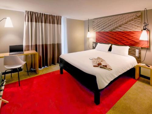 a hotel room with a large bed and a red carpet at ibis Brest Kergaradec in Brest