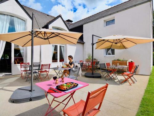 a woman sitting at a table under an umbrella at ibis Brest Kergaradec in Brest