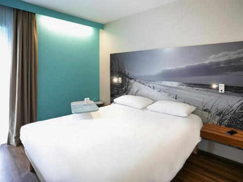 a bedroom with a bed and a picture of a beach at ibis Styles Quimper in Quimper