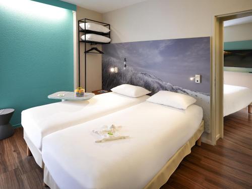 two beds in a room with a painting on the wall at ibis Styles Quimper in Quimper