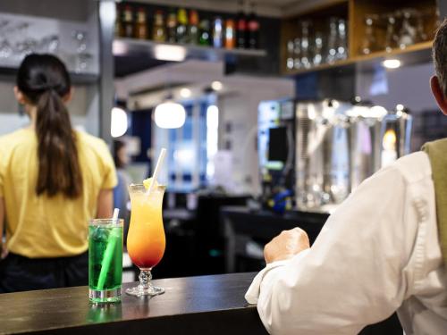 a man sitting at a bar with two drinks on a table at ibis Styles Quimper in Quimper
