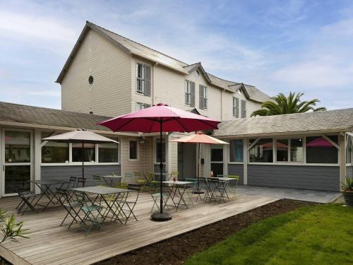 a patio with tables and umbrellas in front of a house at ibis Styles Quimper in Quimper