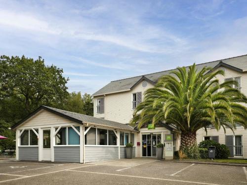 a palm tree in front of a building at ibis Styles Quimper in Quimper