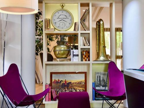 a room with purple chairs and a clock on a shelf at ibis Maisons Laffitte in Maisons-Laffitte