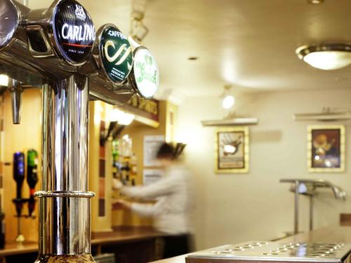 a woman standing in a kitchen with a coffee machine at ibis Carlisle City Centre in Carlisle