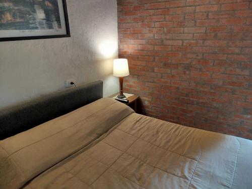 a bedroom with a bed with a lamp and a brick wall at HOSTAL CASA DE GUADUA/ THE BAMBOO HOUSE in Choachí