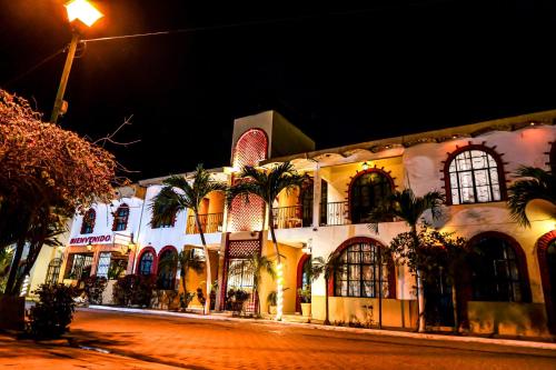 a building with palm trees in front of it at night at Bungalows Maria Teresa in Rincon de Guayabitos