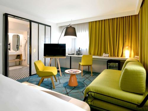 a hotel room with a bed and a couch and chairs at Mercure Nantes Centre Gare in Nantes