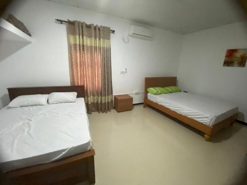 ein Schlafzimmer mit zwei Betten und einem Fenster in der Unterkunft Rooms trincomalee in Trincomalee
